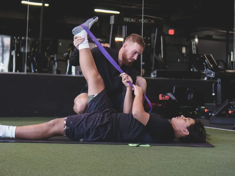 Matt stretching a young athlete's hamstring with a band