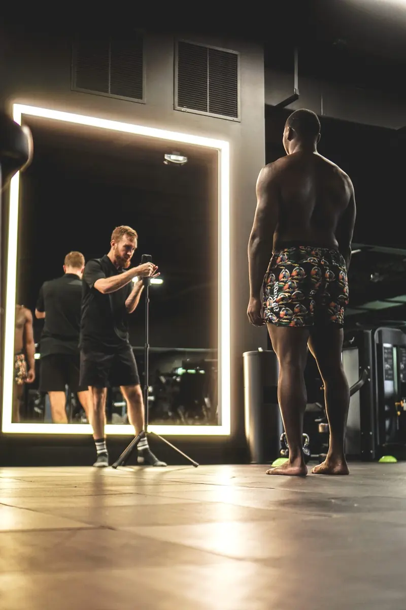 Matt filming Owen Carney's posture in a lit mirror during a movement assessment